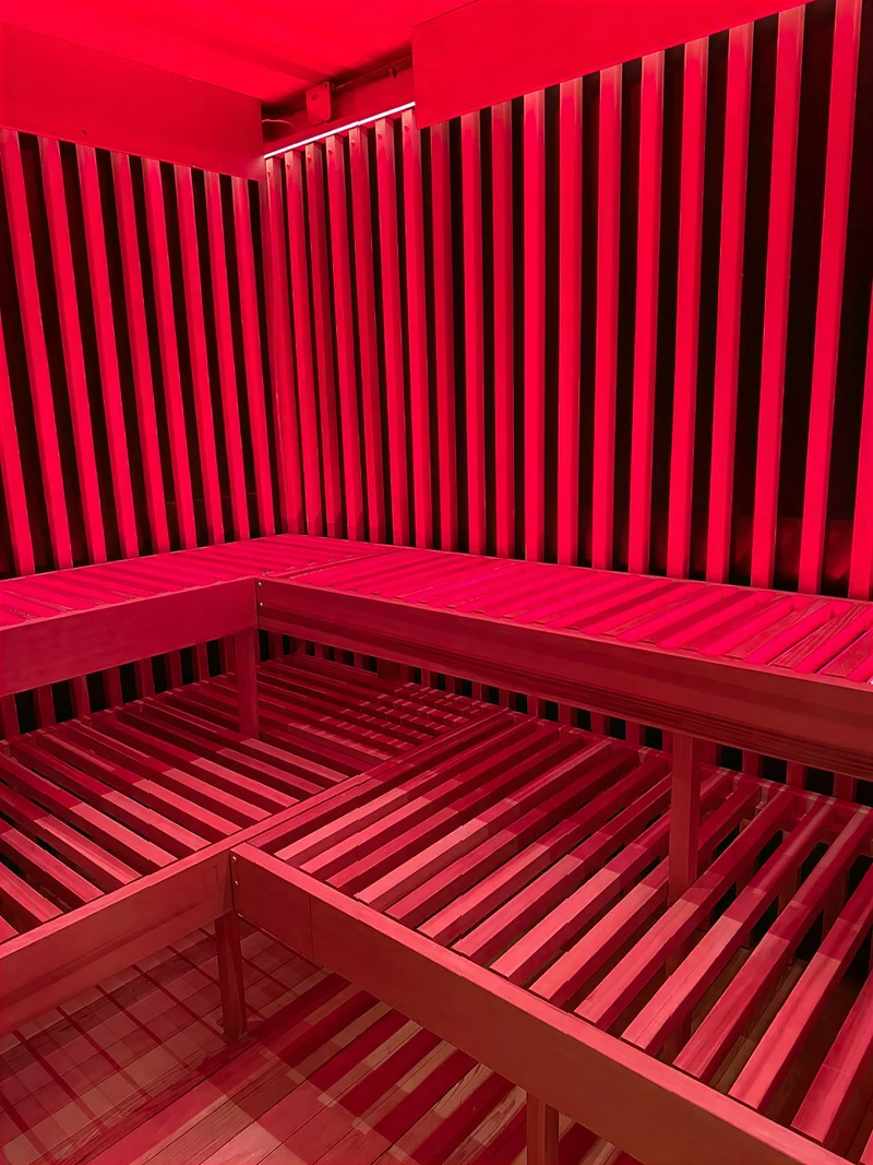 Sauna interior with red light panels above a solid wood bench