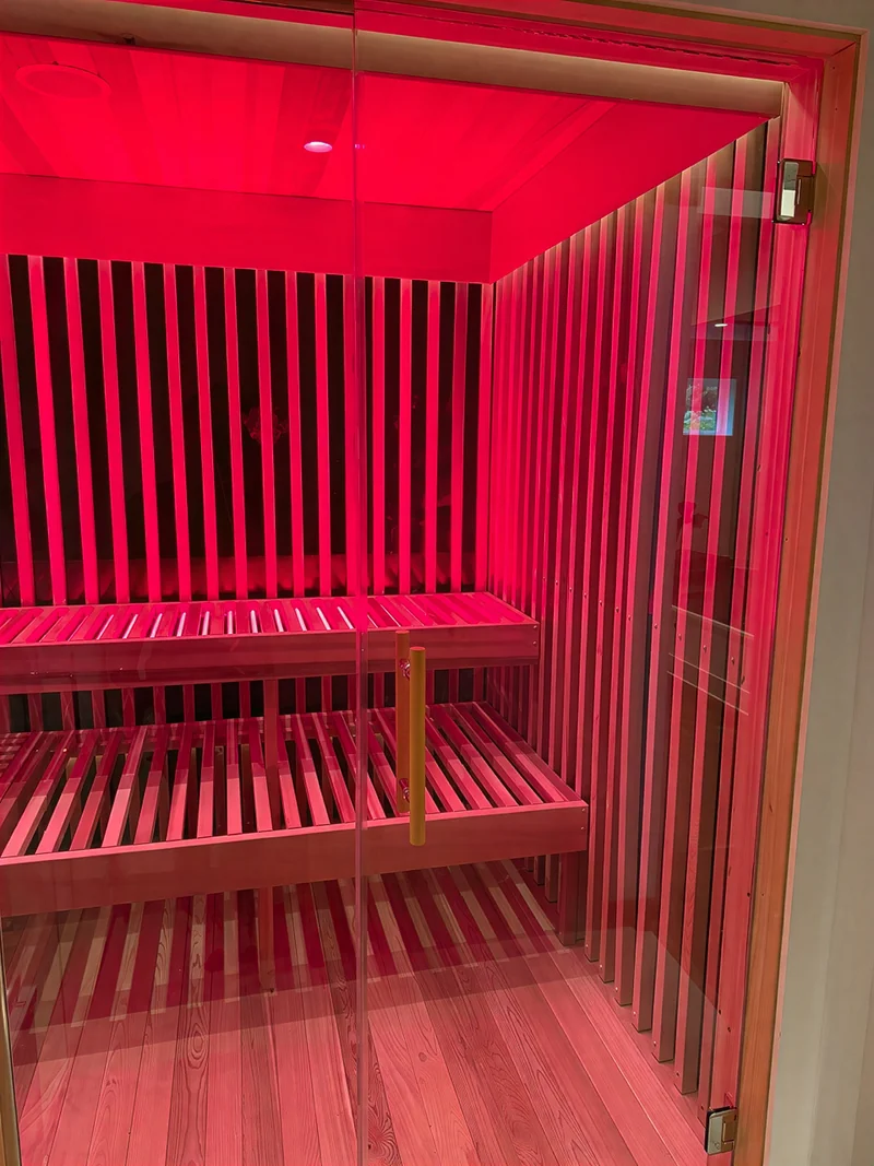 Sauna with a full glass door and red light therapy inside