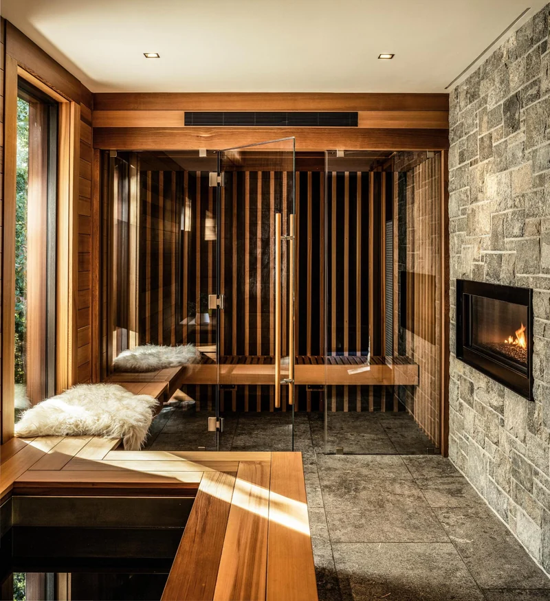 Glass sauna in a living space with a stone fireplace