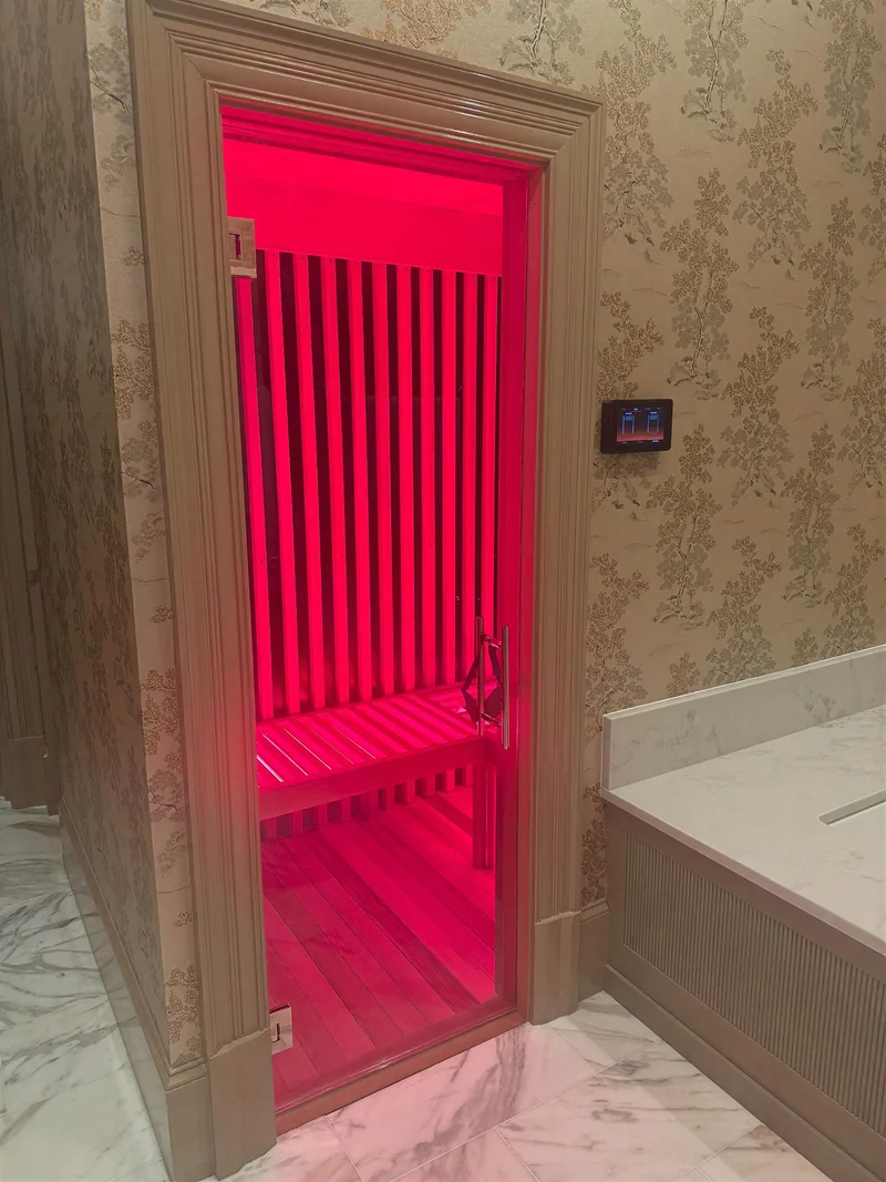 Sauna entry with red interior lighting seen from a bathroom